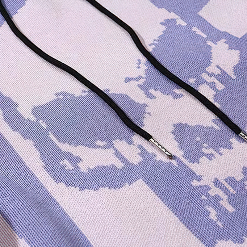 Close-up of a knitted hoodie showing a colorful skull print and contrasting drawstrings for a trendy streetwear look.