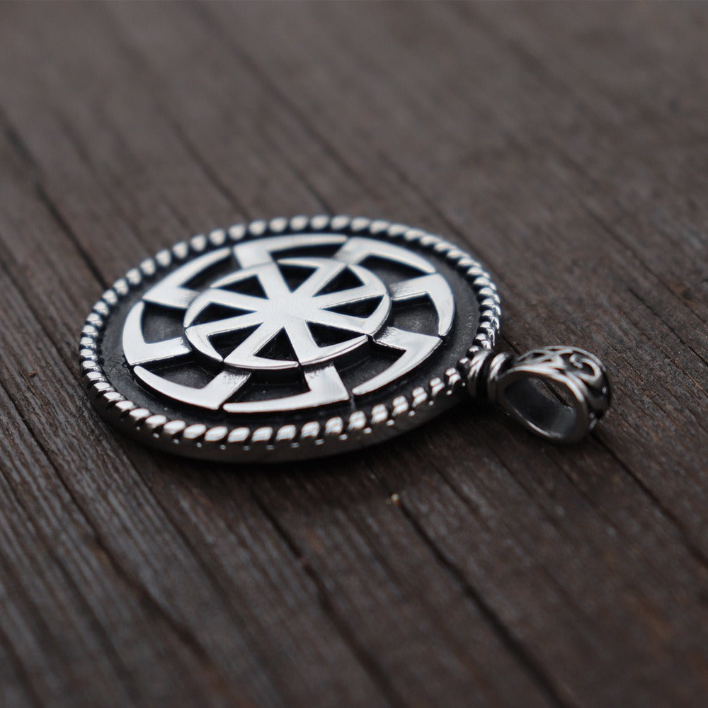 Kolovrat Pagan stainless steel pendant on wooden background, featuring intricate Slavic sun symbol design.
