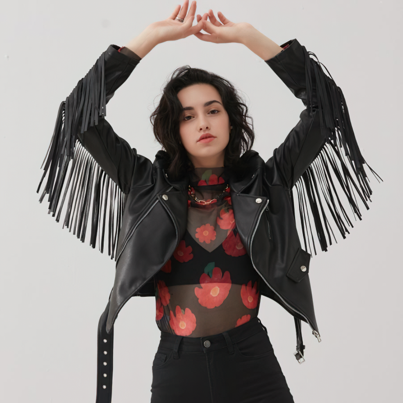 Stylish women in a black PU leather biker jacket with fringe, showcasing rock style and confidence.