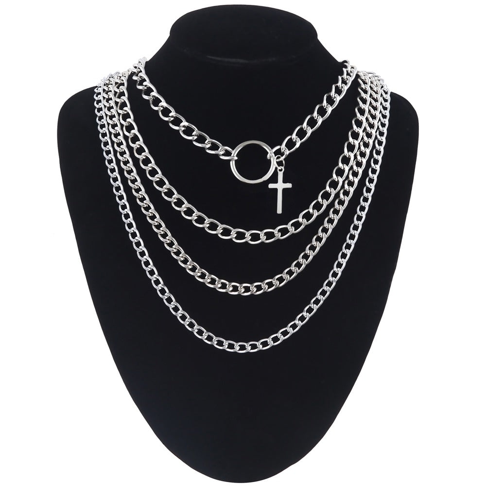 Layered silver chain necklace with cross and ring on a display bust, unisex fashion accessory.