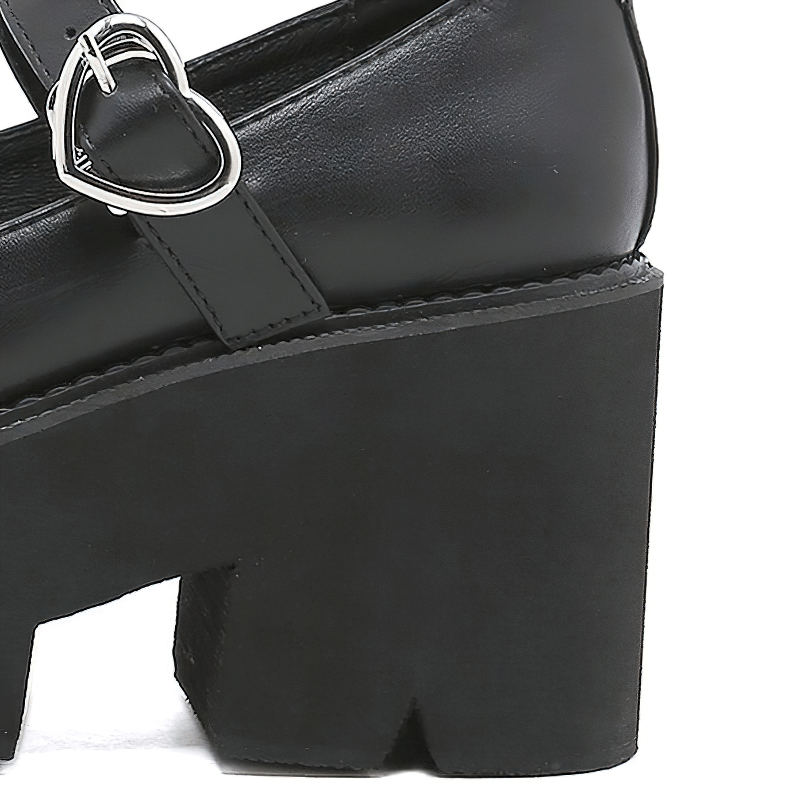 Close-up of stylish black Lolita platform shoes with a heart buckle and thick heel for women.