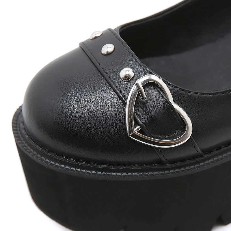 Close-up of women's black Lolita platform shoes featuring a heart buckle and studded details.