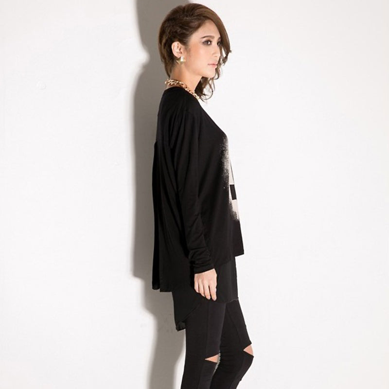 Stylish woman in a long sleeve black chiffon top, showcasing its loose fit and unique print against a clean background.