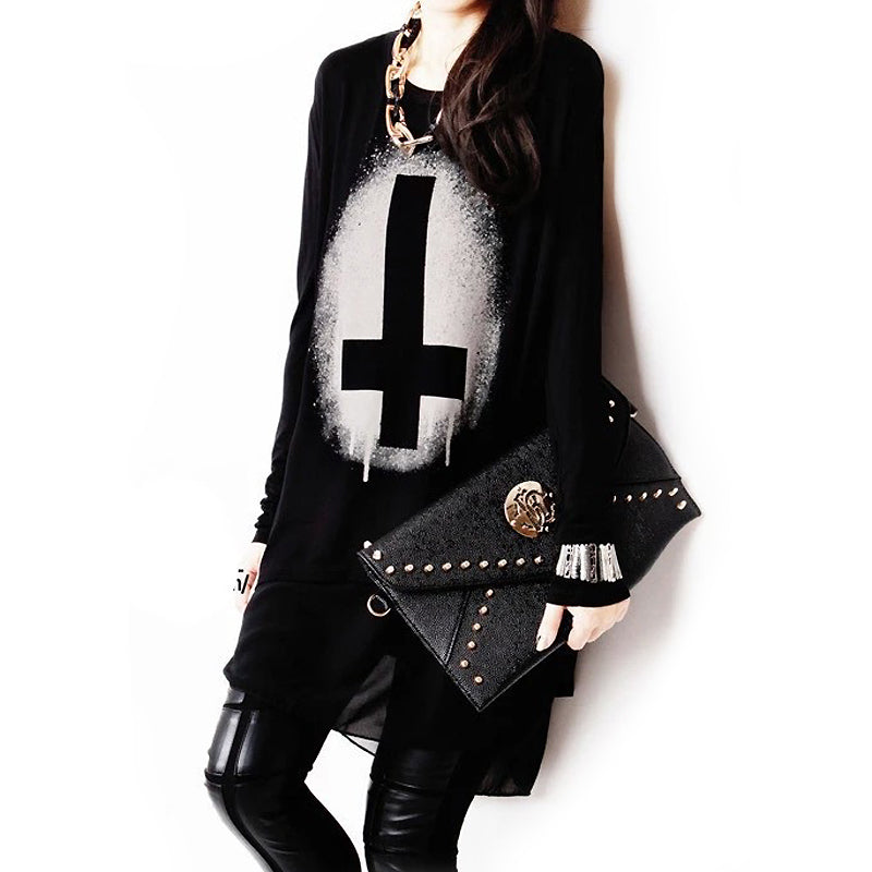 Model wearing a long sleeve black gothic sweater with a graphic print, holding a studded black clutch.