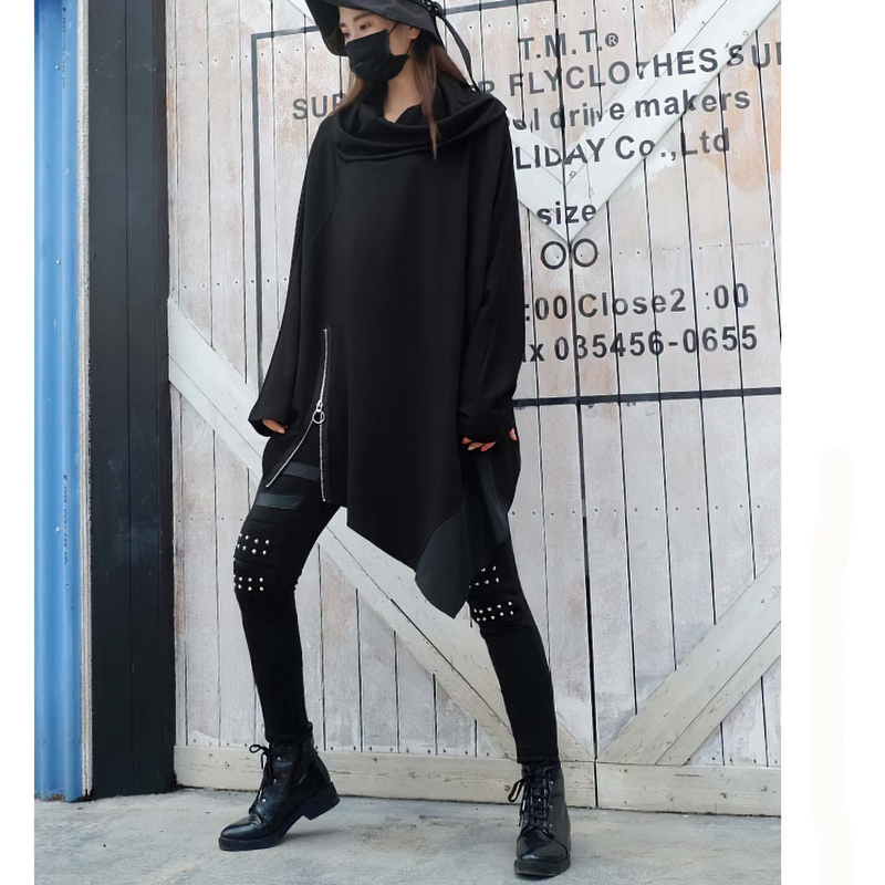 Model wearing oversized black asymmetrical sweatshirt with stylish zipper and accessories, showcasing casual chic style.