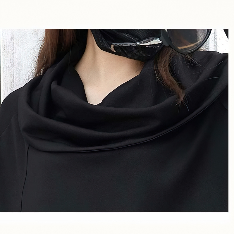 Close-up of a woman wearing a loose fit black asymmetrical sweatshirt with a stylish cowl neck.