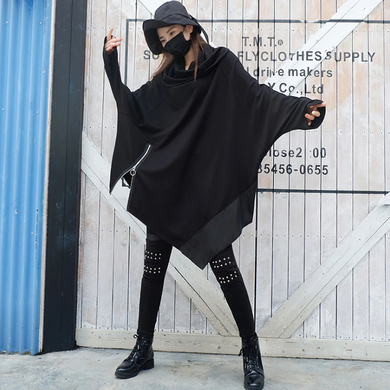Stylish woman in an oversized asymmetrical black sweatshirt paired with edgy leggings and accessories.