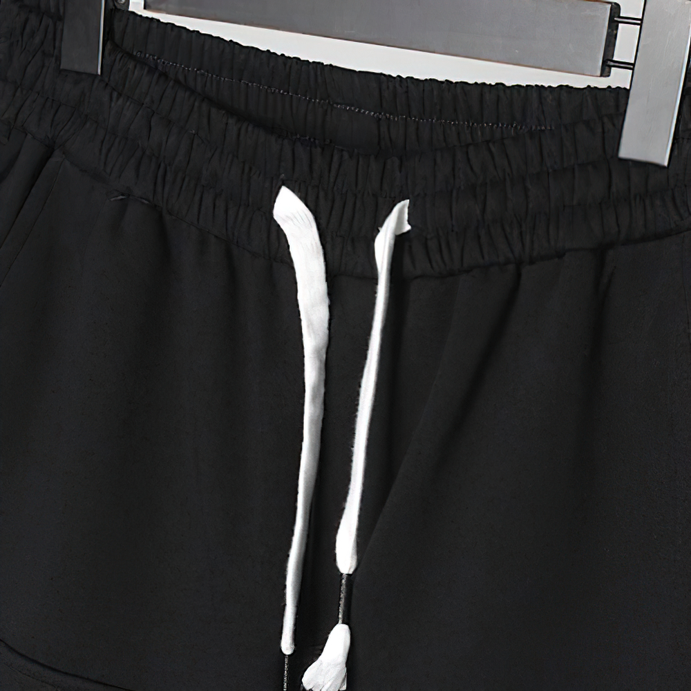 Close-up of black men's pants with elastic waistband and drawstring for comfort, ideal for casual wear.
