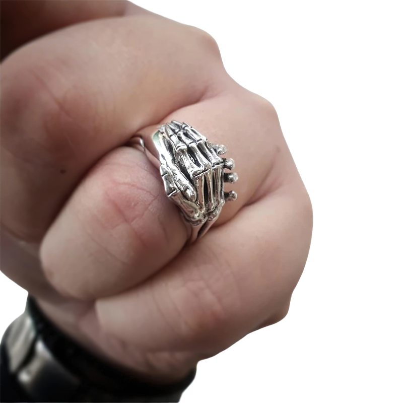 Close-up of a skeleton hands puzzle ring on a person's fist, showcasing alternative stainless steel jewelry.