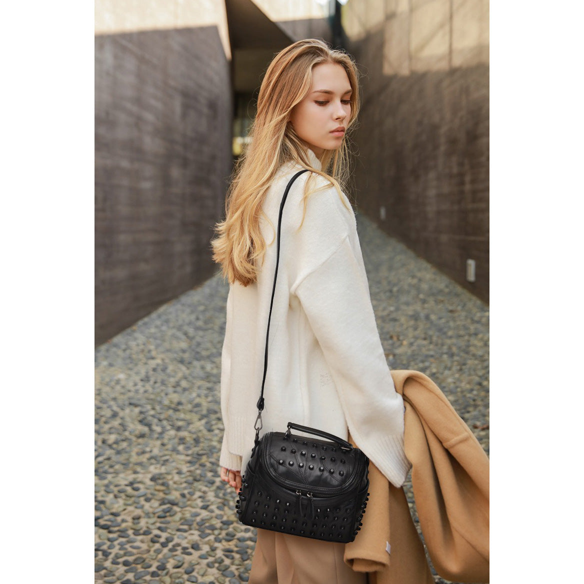 Luxury black women's sheepskin messenger bag, perfect for daily outings and stylish events, featuring rivets and a single strap.