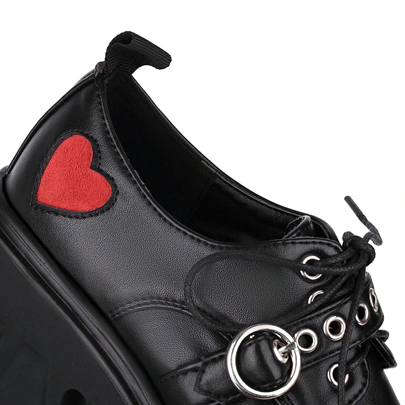 Close-up of luxury women's chunky pumps with a red heart detail on sleek black leather. Perfect for gothic fashion.