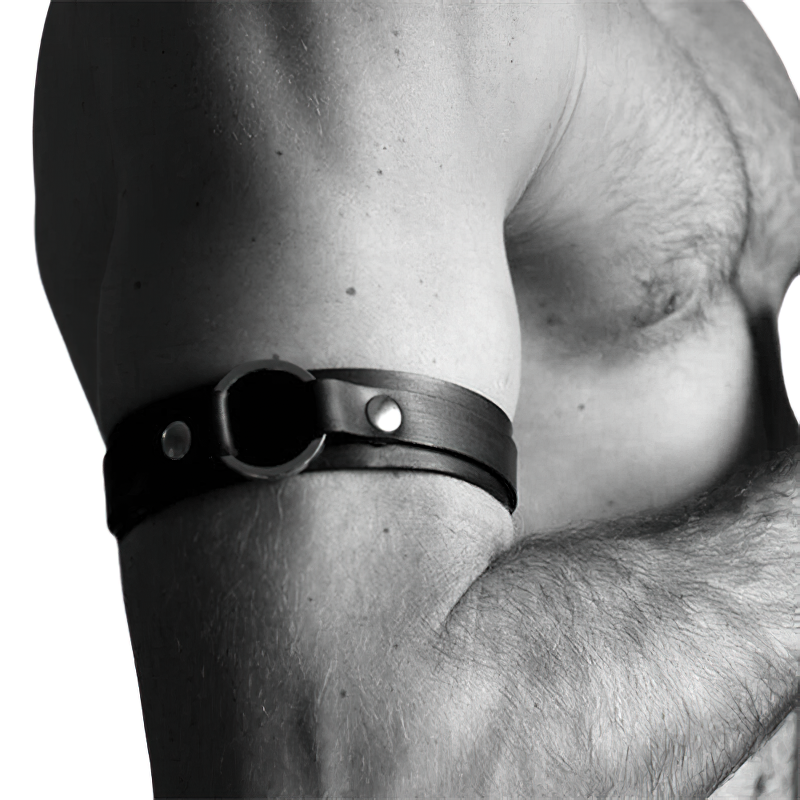 Close-up of a muscular man's arm with a black leather armband, highlighting punk style and edgy accessories.