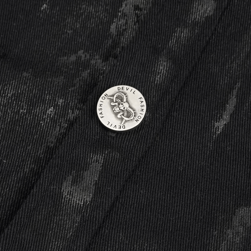 Close-up of metal decoration on a black distressed punk shirt featuring devil design for a stylish touch.