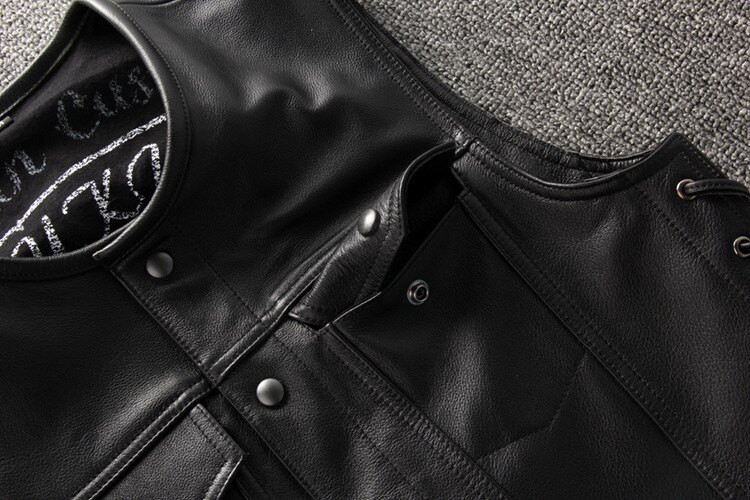 Close-up of a black genuine leather motorcycle vest showcasing snap closures and stylish laces for a rugged biker look.