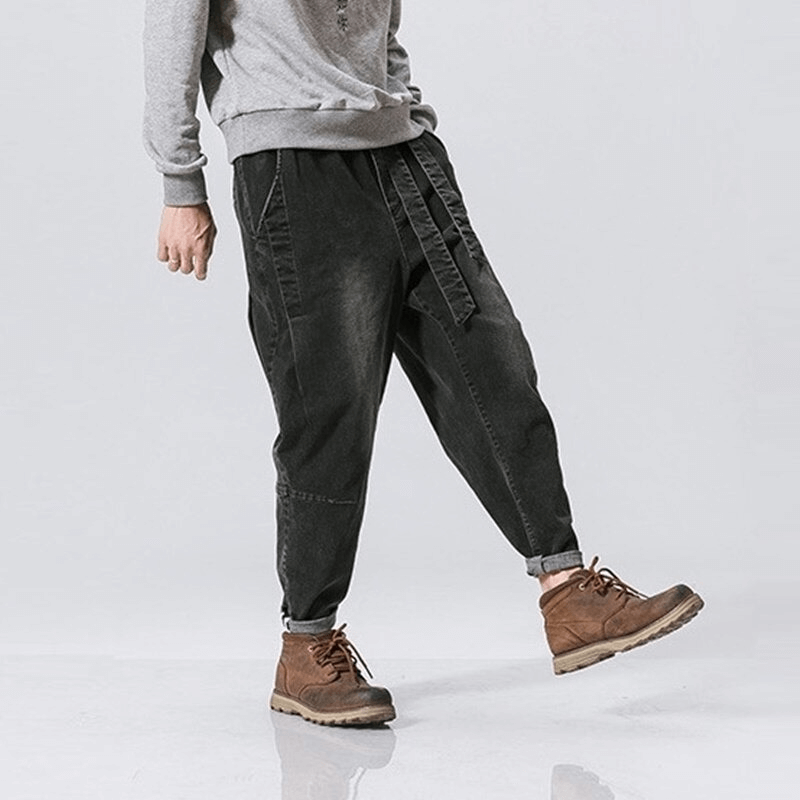 Stylish men's loose denim pants with belt, paired with a sweater and boots for a casual look.