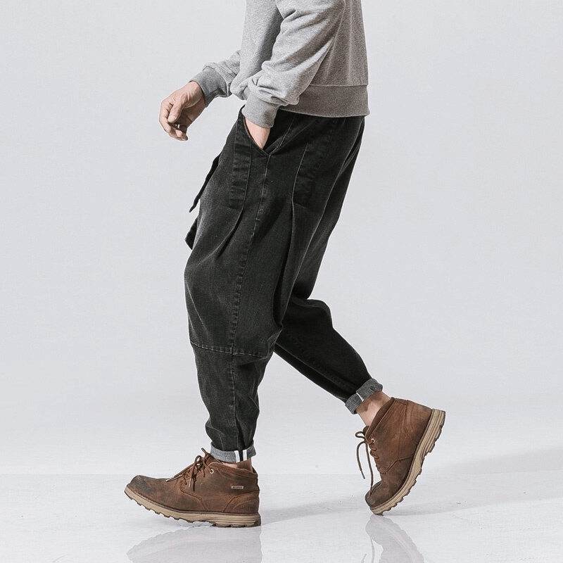 Stylish male in loose black denim pants paired with brown boots, showcasing casual fashion.