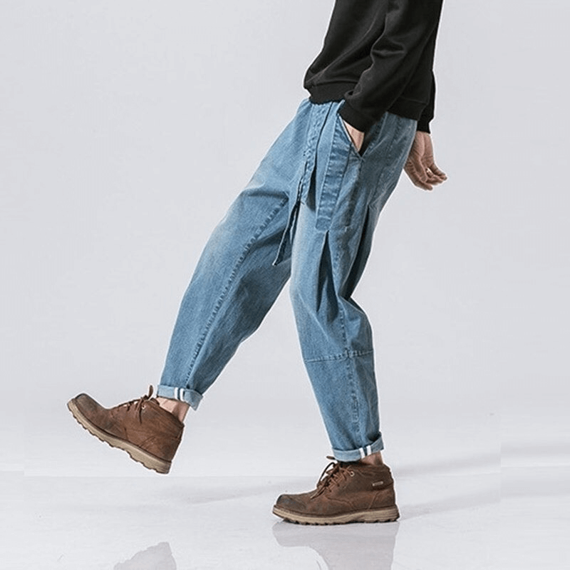 Stylish male model wearing loose denim pants with belt, showcasing a casual look in light blue jeans.