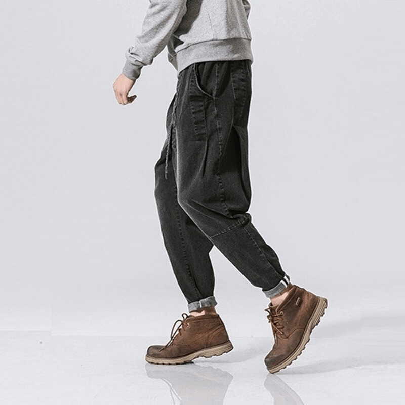 Stylish male wearing loose denim pants with belt, paired with casual sweater and boots, showcasing a trendy look.