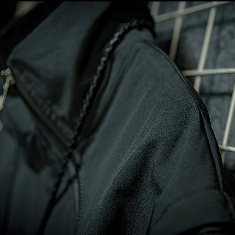 Close-up of a stylish men's black patchwork jacket featuring a stand collar and zipper detail.