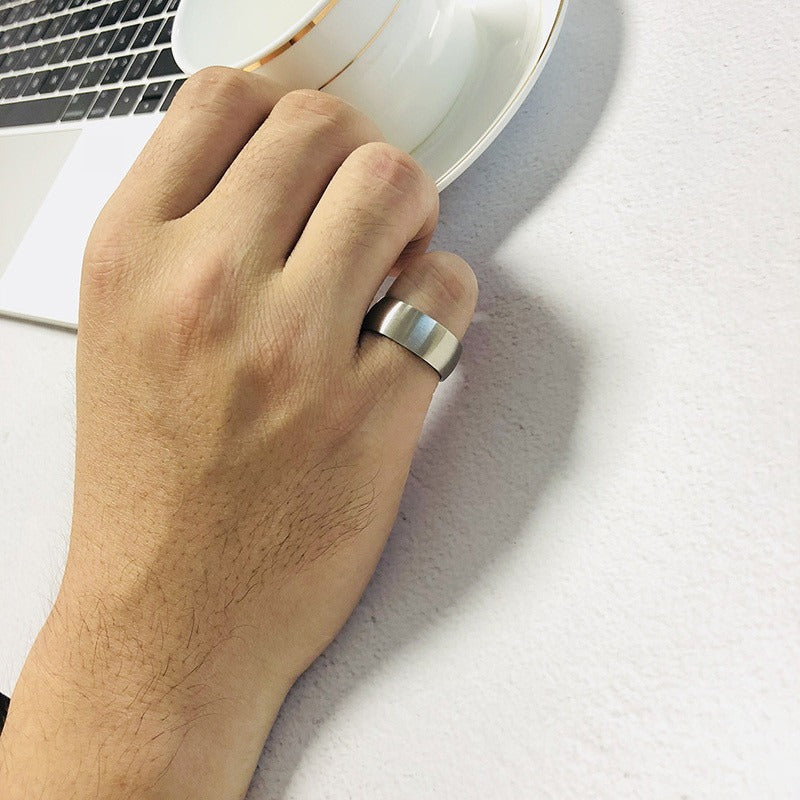 Hand wearing a matte stainless steel ring with a black inner, showcasing alternative jewelry style.