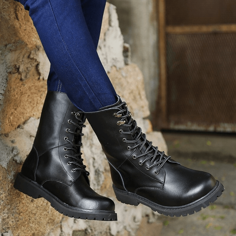 Men's black combat boots showcasing a lace-up design, perfect for casual and tactical wear, paired with jeans.