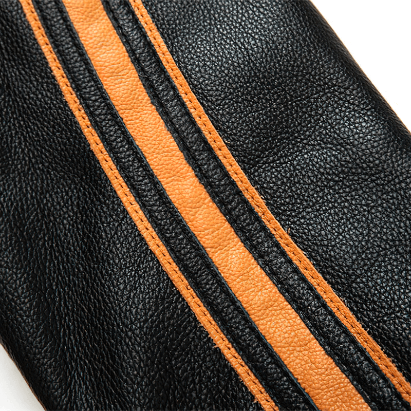 Close-up of textured black leather with an orange stripe, showcasing quality craftsmanship and style for motorcycle jackets.