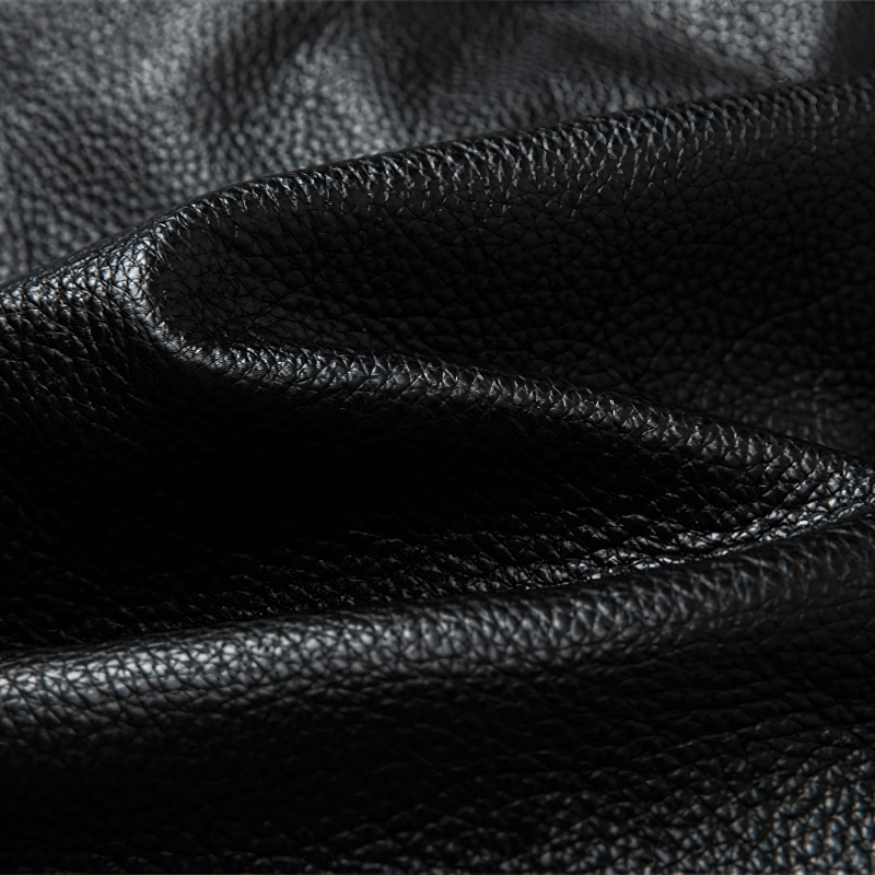 Close-up of premium black genuine leather, showcasing its rich texture and quality for stylish jackets.