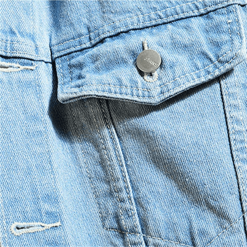 Close-up of a men's denim jacket pocket with stylish stitching and button detail in light blue fabric.