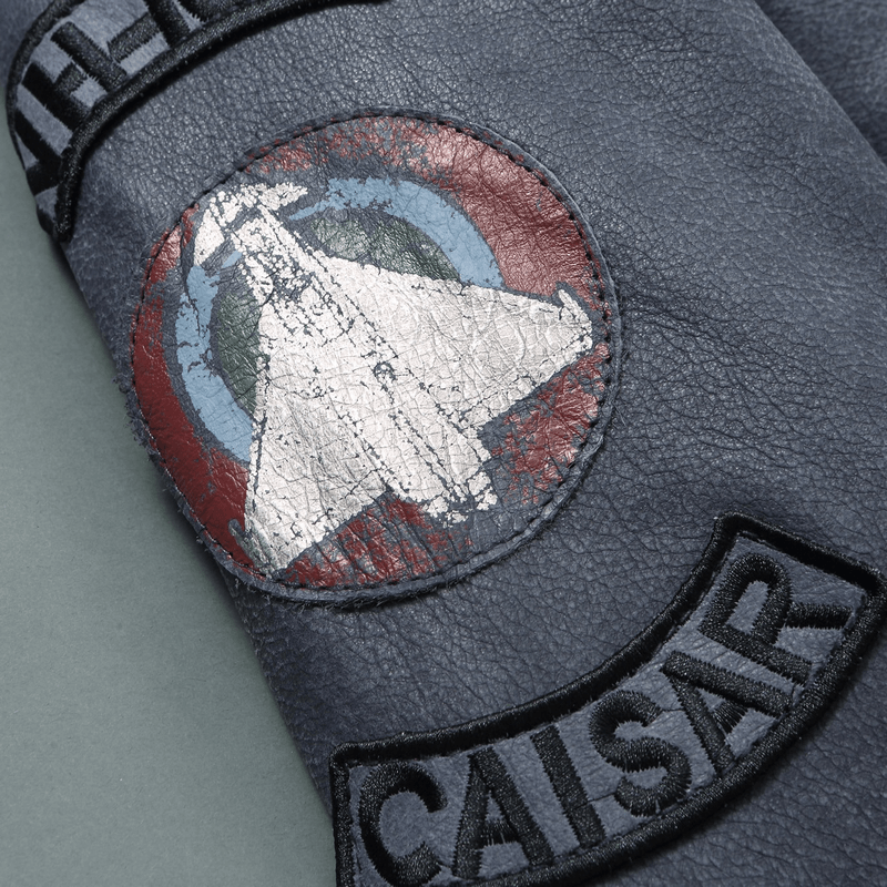 Close-up of a vintage leather jacket with detailed patches featuring a spaceship design and the name CAISAR.