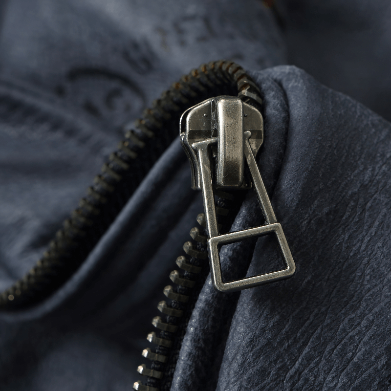 Close-up of the sturdy zipper on a men's genuine leather motorcycle jacket, featuring a smooth blue finish.
