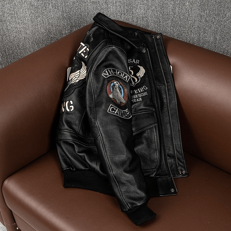 Men's genuine leather motorcycle jacket with patches and big pockets draped on a brown couch.