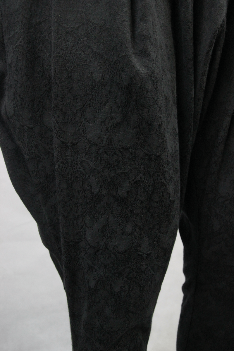 Close-up of men's gothic baggy black trousers featuring a delicate patterned fabric, perfect for a stylish casual look.