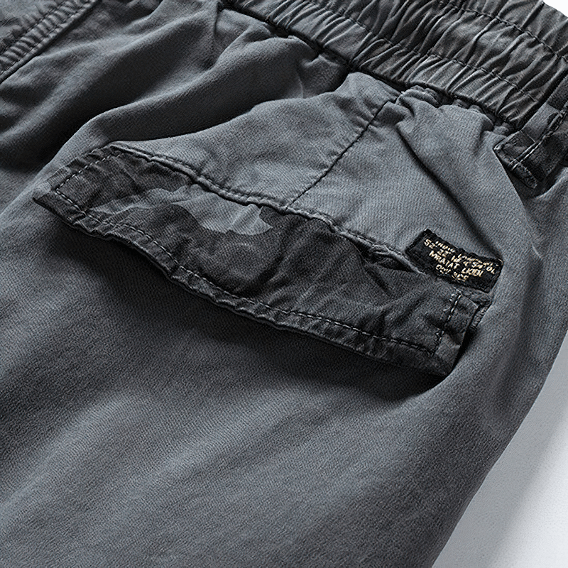 Close-up of men's joggers with elastic waist and camouflage elements, showcasing a casual yet trendy design.