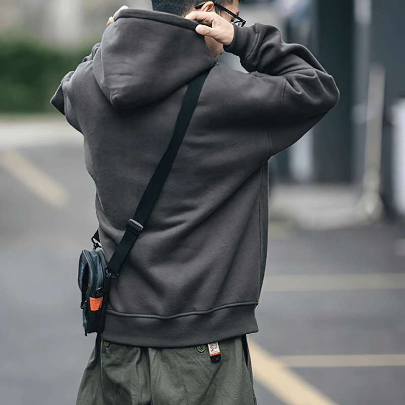 Men's loose-fitting fleece hoodie with drawstring hood worn outdoors, showcasing alternative style and casual fashion.