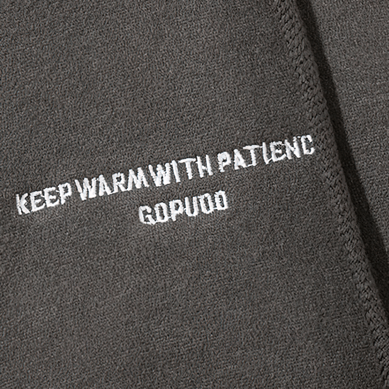 Close-up of a gray hoodie fabric with the phrase 'Keep warm with patience' embroidered in white.