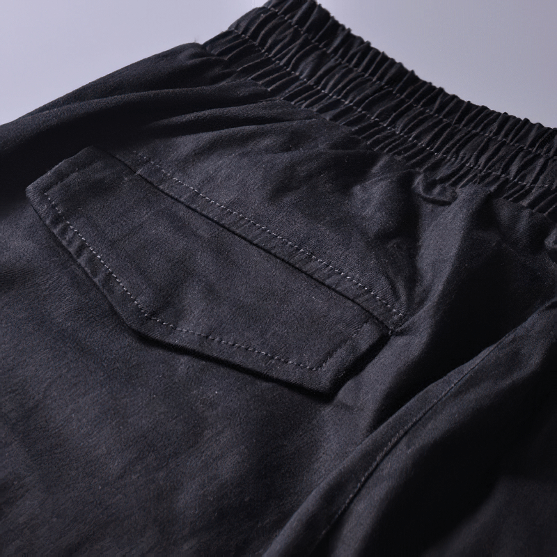 Close-up of men's black cargo joggers showing elastic waistband and back pocket for functional style and comfort.