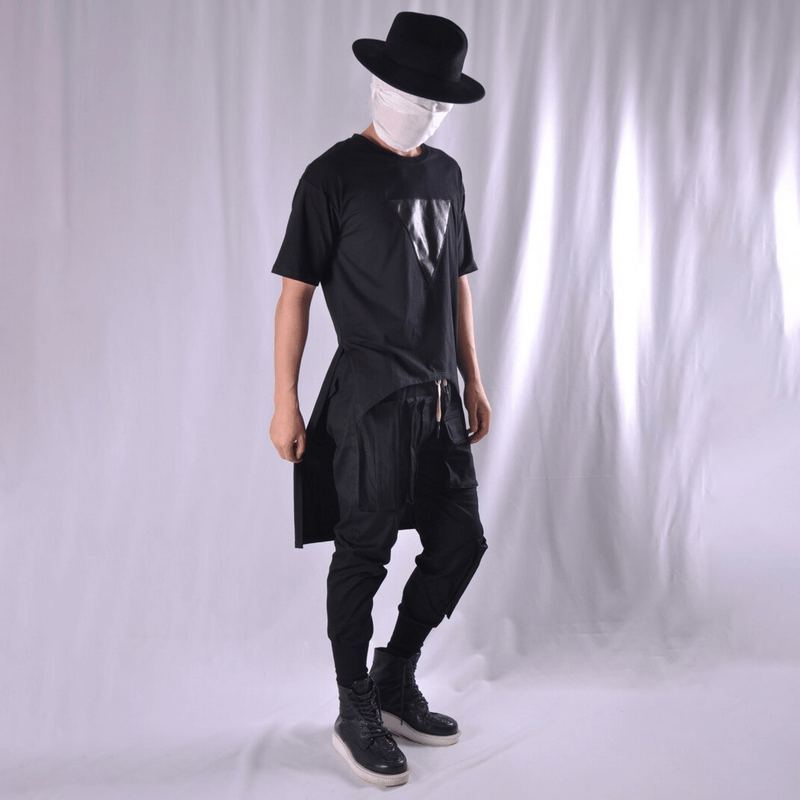 Stylish man in black outfit with multi-pocket joggers and hat, showcasing alternative fashion style.