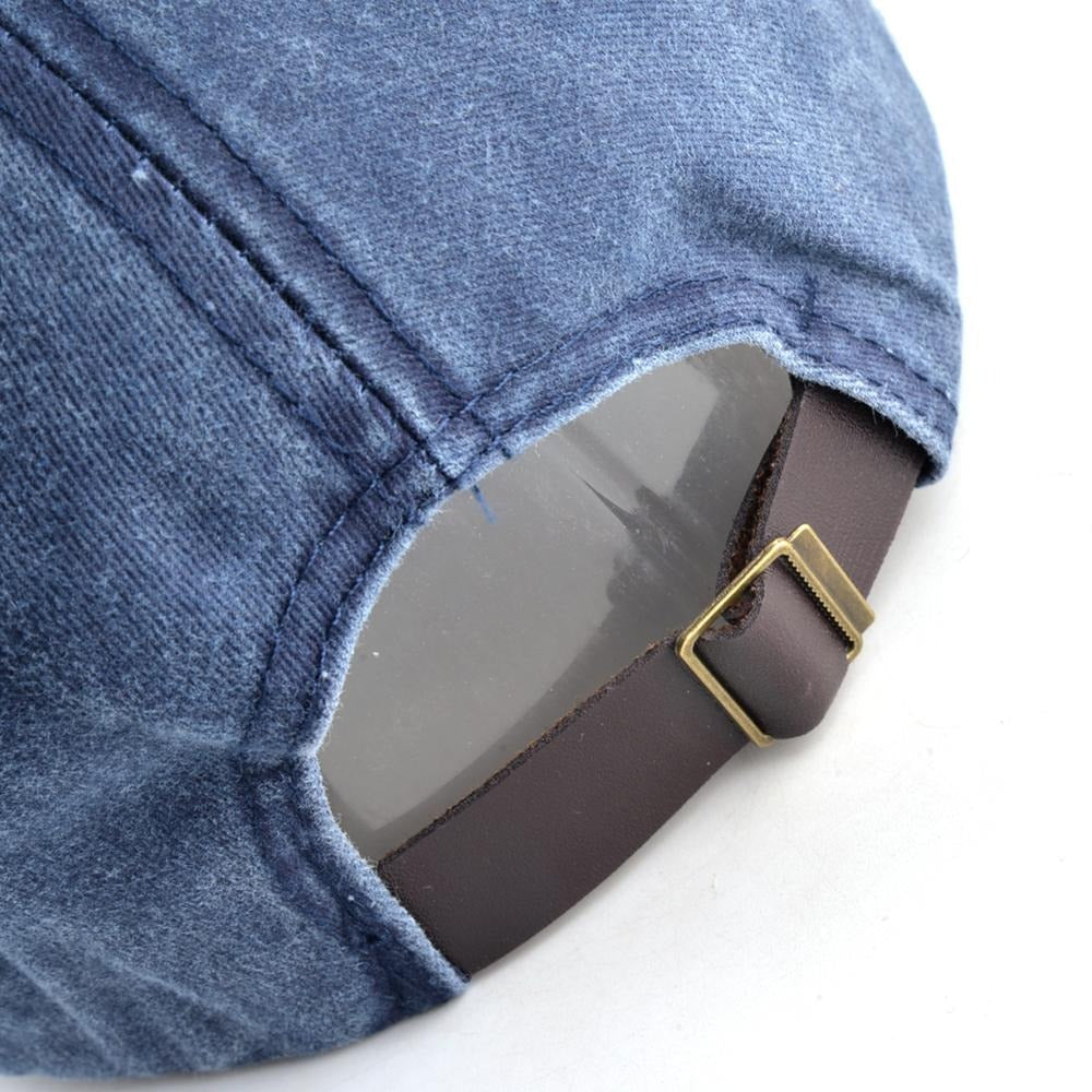Close-up of adjustable snapback strap on a washed denim baseball cap with wolf embroidery.