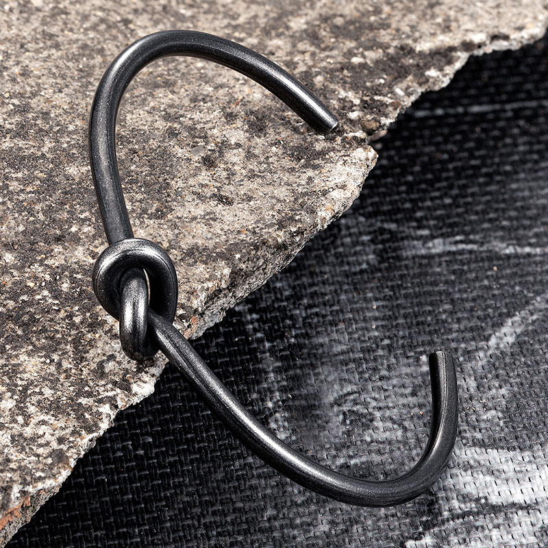 Stylish black alternative hook bracelet design on a textured surface for modern, edgy fashion.
