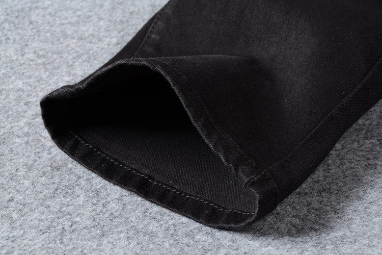 Close-up of the cuff of men's black biker jeans, featuring a sleek design and durable stitching for goth and rock styles.