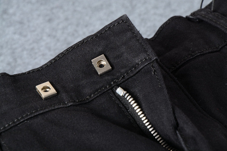 Close-up of men's black biker jeans with silver snap and zipper details, showcasing goth and rock fashion style.