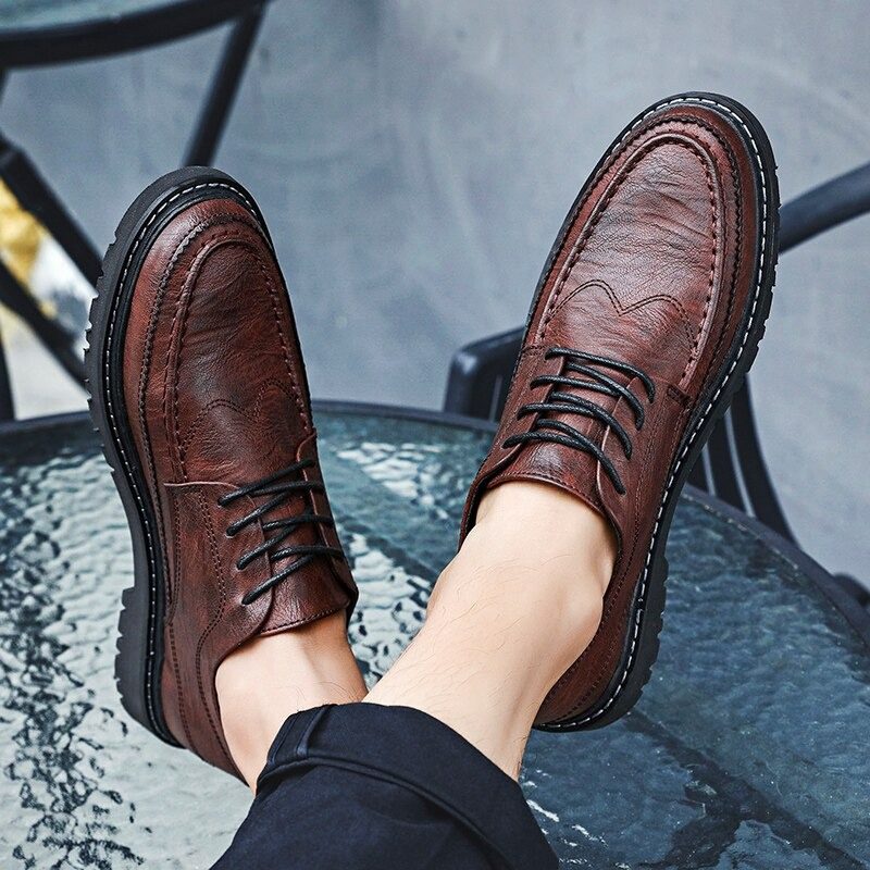 Brown men's leather lace-up dress shoes on a glass table showcasing a stylish and comfortable British design.