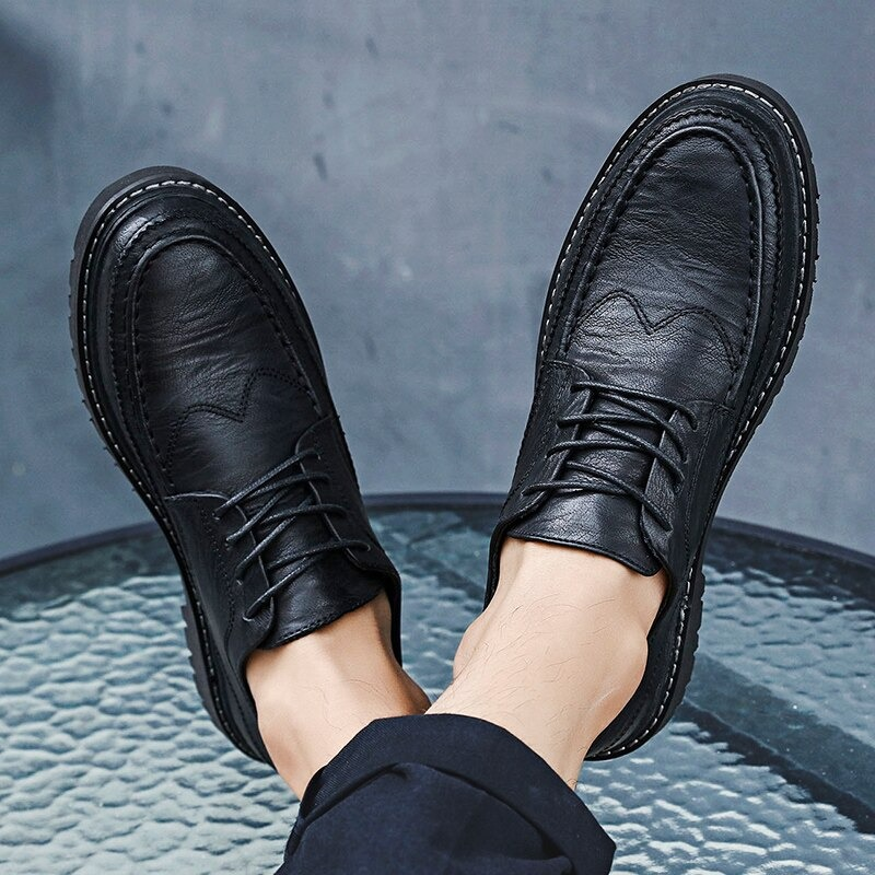 Men's black leather dress shoes with lace-up design on a glass table, perfect for casual fashion and comfort.
