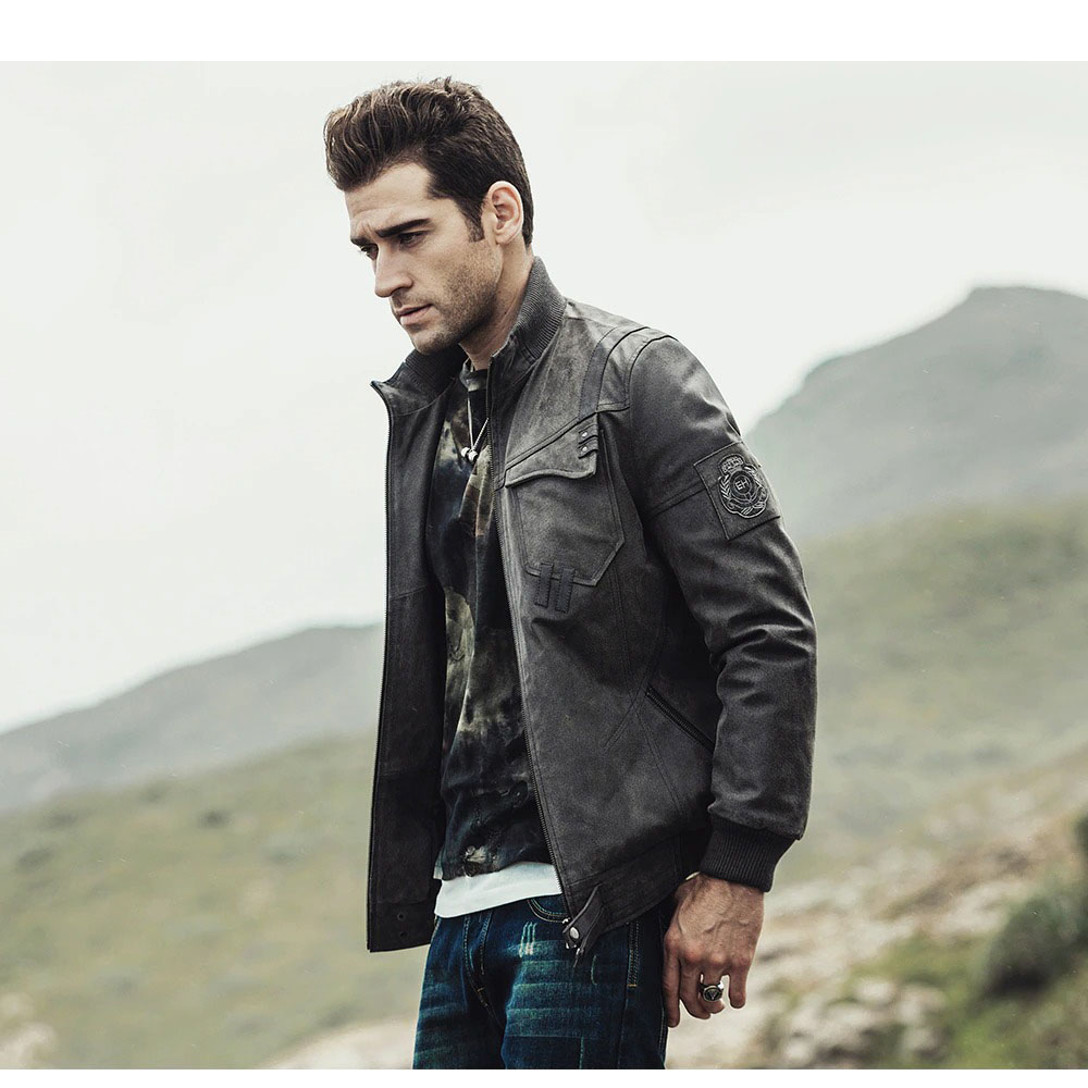 Stylish man wearing a vintage men's leather jacket outdoors with mountains in the background.