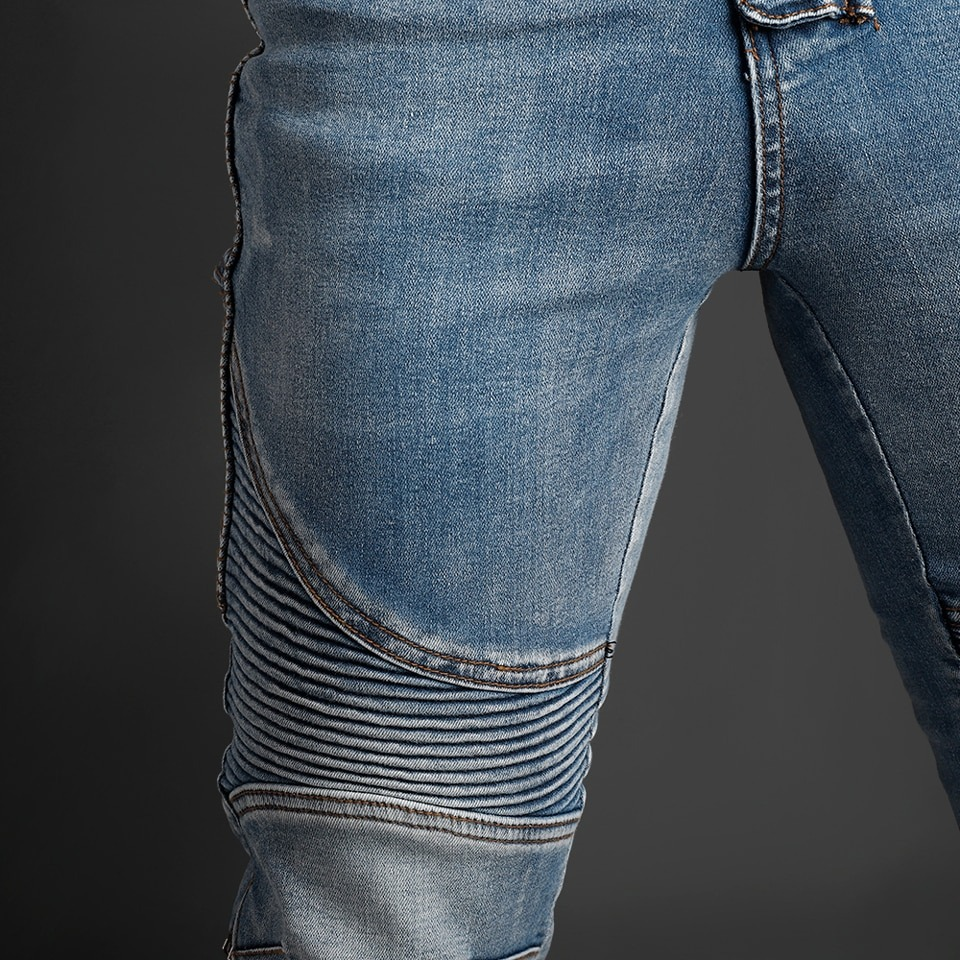 Close-up of men's biker style slim jeans with stylish ribbed detailing and vintage blue wash.