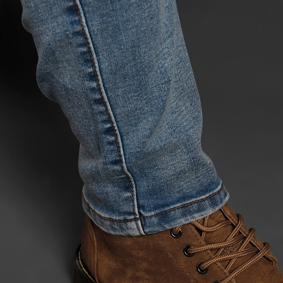 Close-up of men's slim biker jeans paired with stylish brown boots, showcasing quality denim texture and fit.