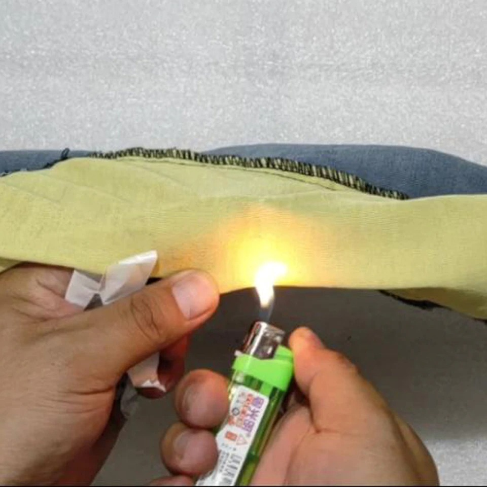 Person using a lighter to test fabric durability on biker style jeans.