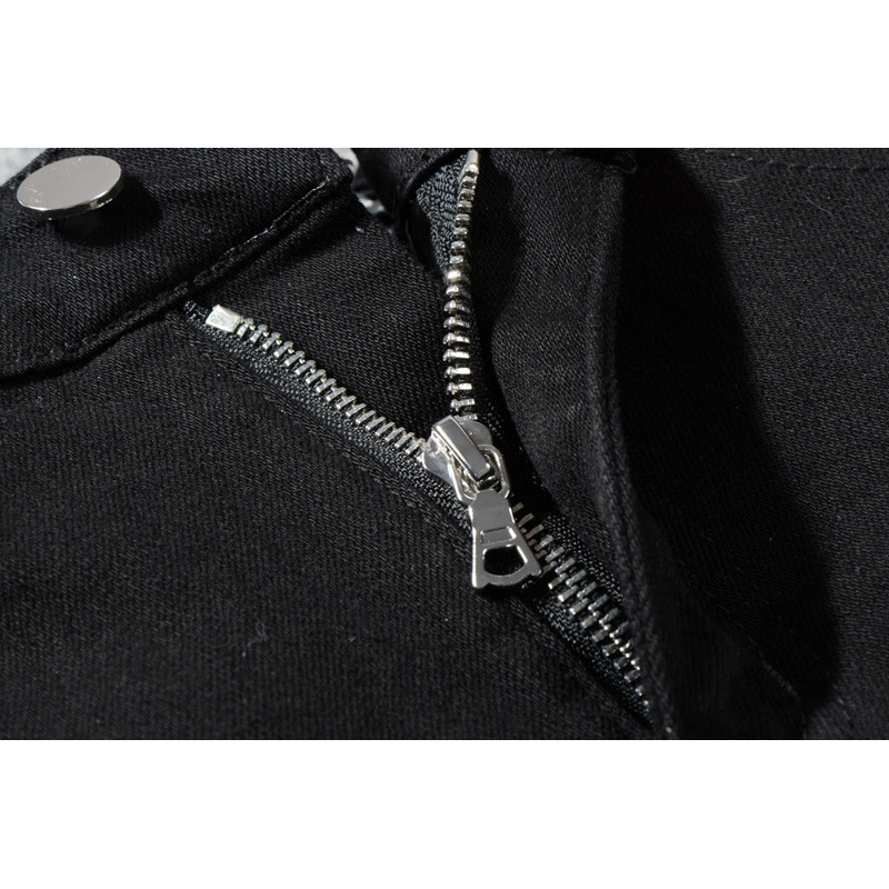 Close-up of the zipper detail on men's slim ripped black denim jeans with rhinestones.