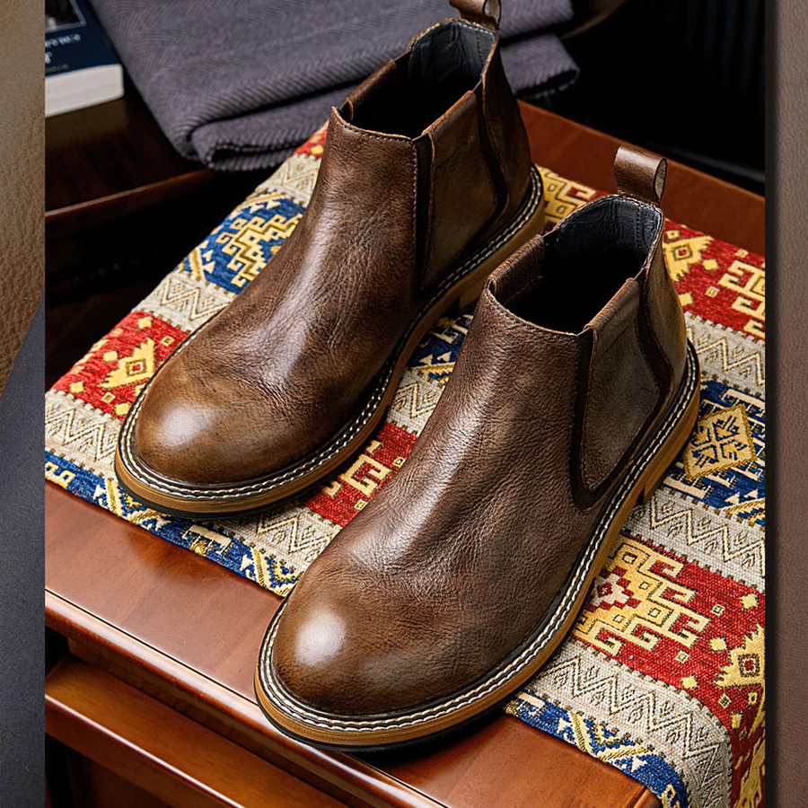 Men's soft leather ankle boots in brown on a colorful patterned fabric background, showcasing casual fashion style.
