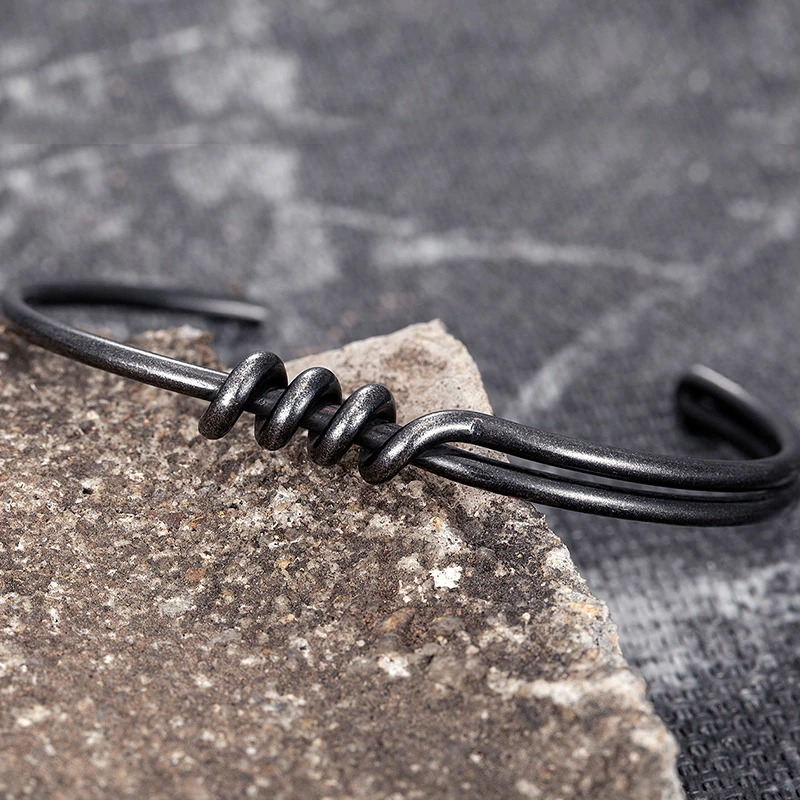 Men's vintage dark gray stainless steel bracelet resting on stone, showcasing a cool rock style.